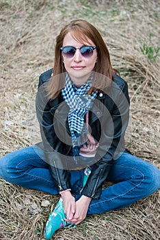 Young woman in a black jacket and jeans sitting on the hay