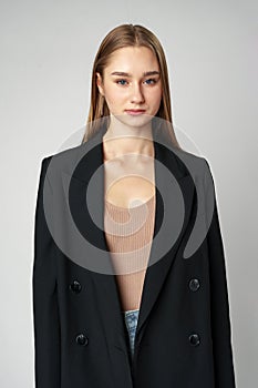 Young Woman in Black Jacket Posing to Camera against gray background