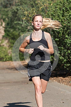 Young woman in black jogs outside.