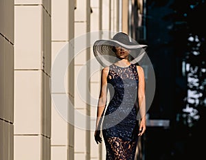 Young woman in black lace dress and a hat with a wide brim.