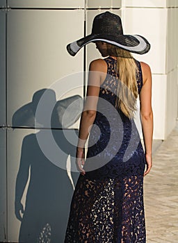 Young woman in black lace dress and hat with a wide brim.