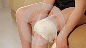 Young woman in black nightie bandages elastic gauze on knee
