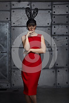 Young woman in black rabbit or hare fancy mask and red dress