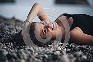 young woman in black skin-tight dress lying on the beach in water