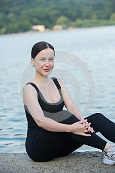 Young woman in black sportswear exercising outdoors. Fitness and healthy lifestyle concept.