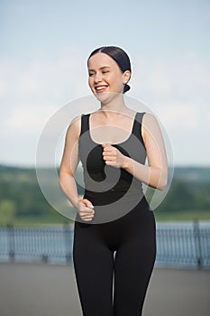 Young woman in black sportswear exercising outdoors. Fitness and healthy lifestyle concept.