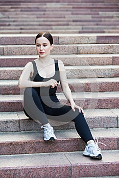 Young woman in black sportswear exercising outdoors. Fitness and healthy lifestyle concept.