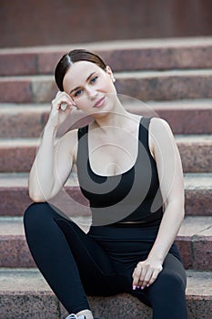 Young woman in black sportswear exercising outdoors. Fitness and healthy lifestyle concept.