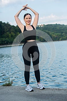 Young woman in black sportswear exercising outdoors. Fitness and healthy lifestyle concept.