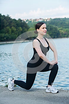 Young woman in black sportswear exercising outdoors. Fitness and healthy lifestyle concept.