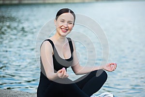 Young woman in black sportswear exercising outdoors. Fitness and healthy lifestyle concept.