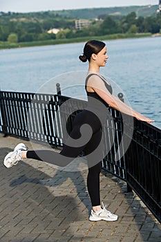 Young woman in black sportswear exercising outdoors. Fitness and healthy lifestyle concept.