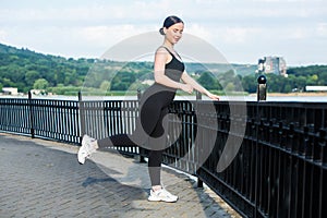 Young woman in black sportswear exercising outdoors. Fitness and healthy lifestyle concept.