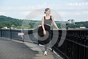 Young woman in black sportswear exercising outdoors. Fitness and healthy lifestyle concept.