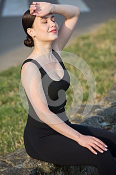 Young woman in black sportswear exercising outdoors. Fitness and healthy lifestyle concept.