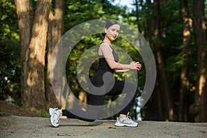 Young woman in black sportswear exercising outdoors. Fitness and healthy lifestyle concept.