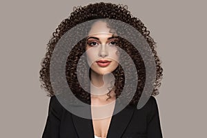 A young woman in a black suit. female hairstyle afro curls. Beauty and fashion portrait