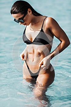 Young sexy woman in black swimwear bikini woman with sunglasses enjoy sea water