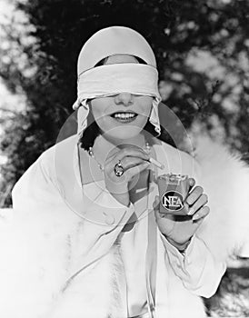 Young woman with blindfolded eyes taking out a cigarette from a cigarette pack