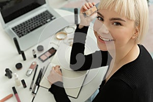 Young woman blogger joyfully shows applying makeup with foundation.