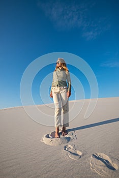 Young woman, blonde with flying hair is walking through the beach