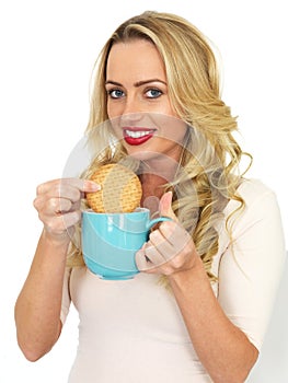 Young Woman With Blonde Hair Relaxing and Dunking a Biscuit in a Mug of Tea