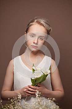 Young woman blonde model with white flowers posing on brown background