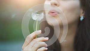 Young Woman Blow on a Dandelion