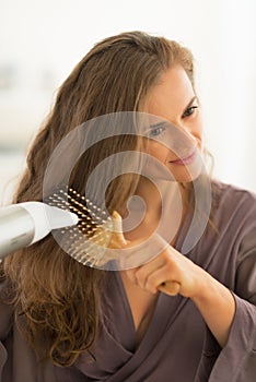 Young woman blow drying hair