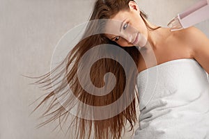 Young woman blow drying hair in bathroom