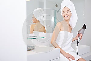 Young woman blow drying hair in bathroom