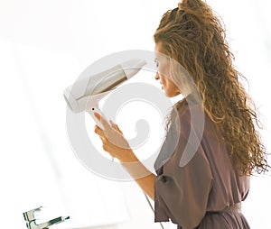 Young woman blow drying hair in bathroom