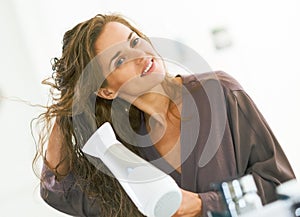 Young woman blow drying hair in bathroom