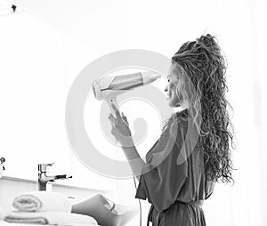 Young woman blow drying hair in bathroom