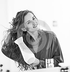 Young woman blow drying hair in bathroom