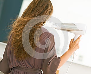 Young woman blow drying hair in bathroom