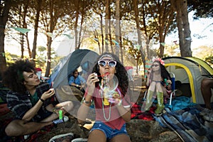 Young woman blowing bubble wand at campsite