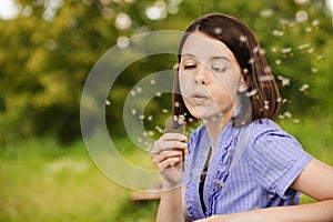 Young woman blowing on dandelion