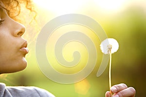 Young woman blowing dandelion flower outdoors