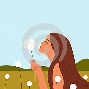 Young woman blowing dandelion in spring field