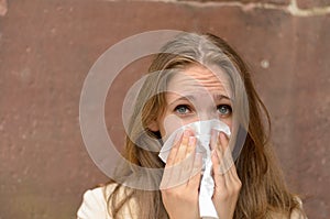 Young woman blowing her nose on a handkerchief