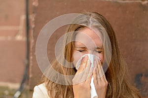 Young woman blowing her nose on a handkerchief