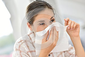 Young woman blowing her nose having cold