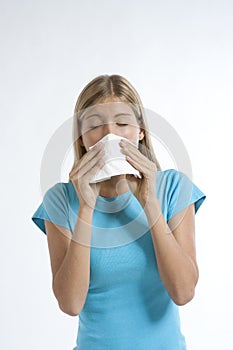 Young woman blowing her nose with kleenex