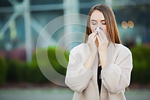 Young woman blowing her nose on the park.