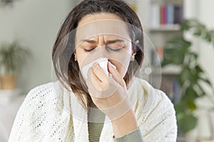 Young woman blowing her nose with a tissue at home