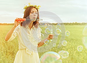 Young woman blowing soap bubbles in summer