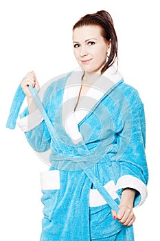 Young woman in blue bathrobe ties waistband