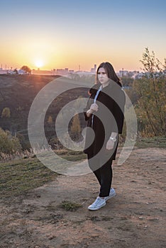 Young woman in a blue blouse and a black coat at sunrise