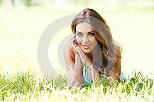 Young woman in blue dress lying on grass